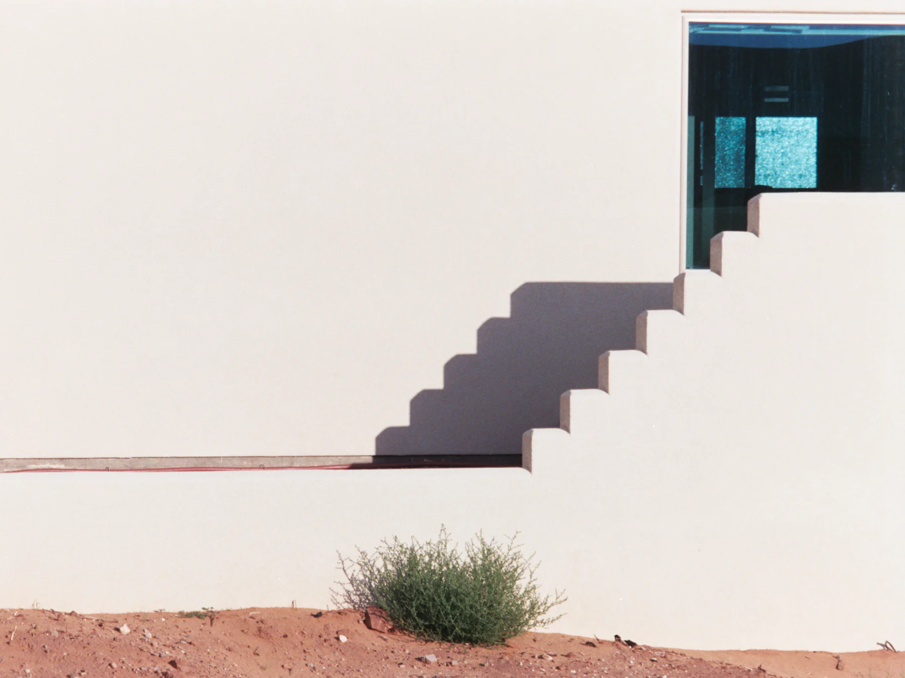 Muro blanco con escalera y su sombra sobre tierra del norte